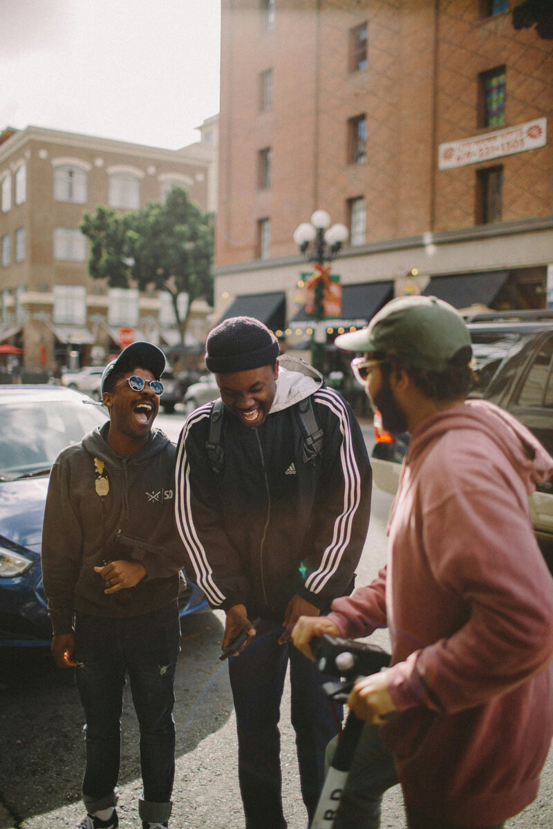 Three male friends laughing on street corner